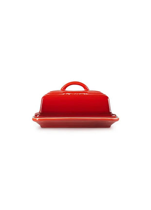 A red ceramic butter dish with a handle on top, sitting on a white background.