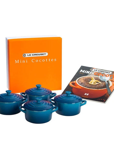 a set of four blue crockery items, including four small blue pots or casserole dishes, along with a box and a cookbook.
